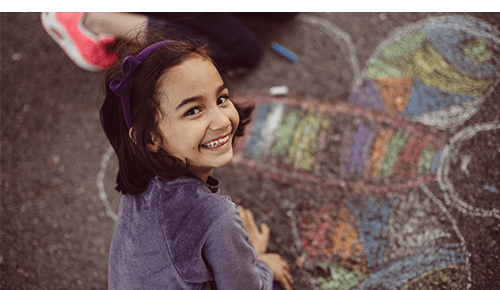 Child drawing with chalk on pavement outside Child drawing with chalk on pavement outside