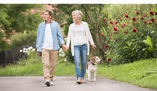 Couple walking their dog on an outdoor path Couple walking their dog on an outdoor path