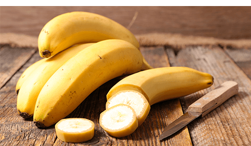 Bunch of bananas with paring knife on wood surface Bunch of bananas with paring knife on wood surface