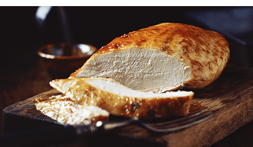 Piece of cooked chicken breast with a slice cut away Piece of cooked chicken breast with a slice cut away