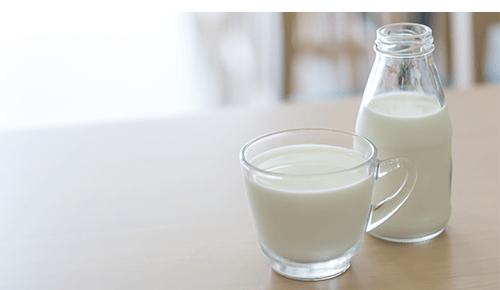 Glass bottle and cup full of milk Glass bottle and cup full of milk