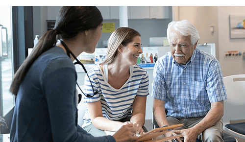 Senior parent and adult child talking to a healthcare provider together Senior parent and adult child talking to a healthcare provider together