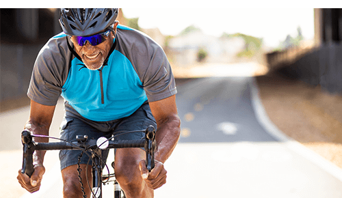 Man with helmet and glasses cycling outdoors on a roadway