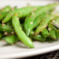 Plate with cooked green beans covered with crushed garlic