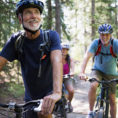 Group of people wearing helmets cycling outdoors on a forest trail