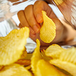 Closeup of inside of potato chip bag with hand pulling a potato chip out