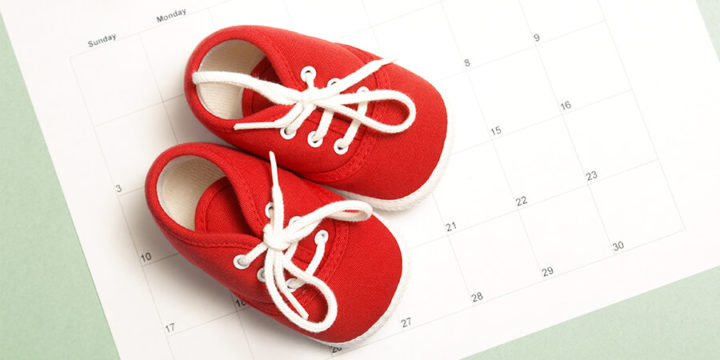 Red baby shoes sitting on top of a calendar