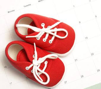 Red baby shoes sitting on top of a calendar