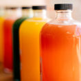 Glass bottles lined up in row and filled with different types of pressed juices