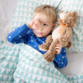 Child laying in bed with stuffed animal