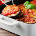 Sliced eggplants and red sauce in a casserole container