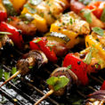 Meat and vegetables on a skewer sitting on a grill