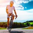 Man wearing helmet riding a bike on a hilly roadway