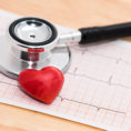 Printed graph from heart monitor with stethoscope and red heart model sitting on top