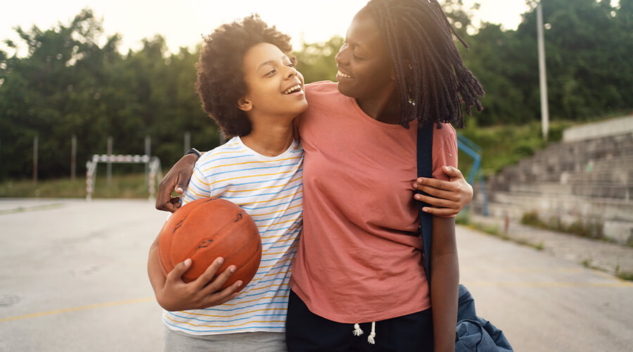 Mother helping child read a book at a dining table