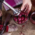 Person mixing beets in a bowl using hand blender