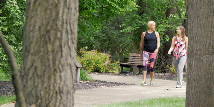 Two women wearing workout clothes while walking on outdoor path