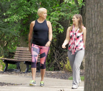 Two women wearing workout clothes while walking on outdoor path