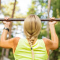 Woman doing pull-ups on an outdoor metal bar