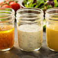 Row of small mason jars filled with different salad dressings