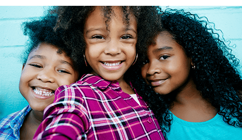 Three children smiling into camera Three children smiling into camera