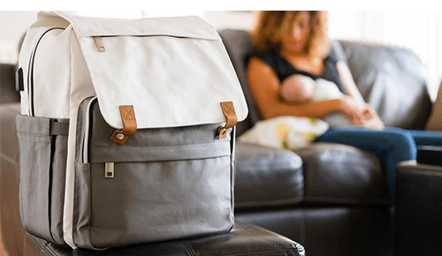 Closeup of a diaper bag sitting on table near a mother breastfeeding her baby Closeup of a diaper bag sitting on table near a mother breastfeeding her baby