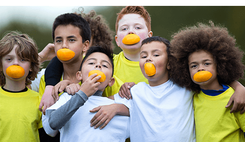 Group of children smiling and eating orange slices during sporting event Group of children smiling and eating orange slices during sporting event