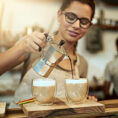 Barista pouring coffee into a small mug in a cafe