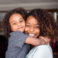 Mother and child hugging and smiling into camera