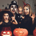 Family dressed up for Halloween and making funny faces in front of pumpkins