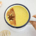 Mug of golden milk with spices on table next to it