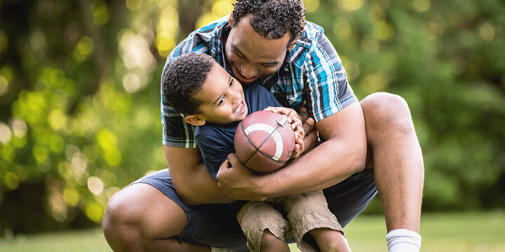 Father and son playing football outside