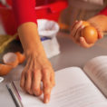 Person using finger to read directions from a cook book on kitchen counter