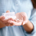 Closeup of hand shaking pills out of a bottle