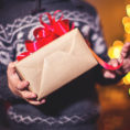Closeup of person holding a wrapped gift with a ribbon on top