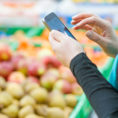 Person looking at phone in fruit aisle of grocery store