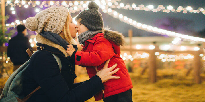 Mother and child kissing under holiday lights