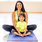 Mother and child stretching on a mat in a gym
