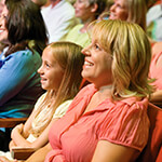 Mother and child looking at stage while seated in theater seats