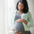 Pregnant person holding stomach thoughtfully