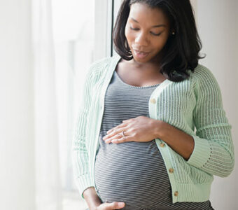 Pregnant person holding stomach thoughtfully