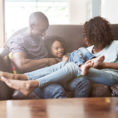 Couple and child laughing and sitting together on couch