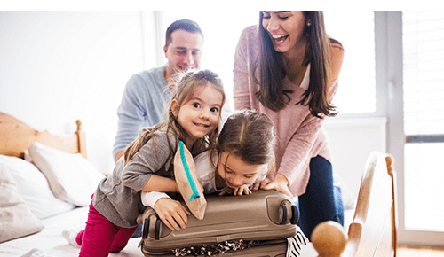 Family with two children packing a suitcase in bedroom Family with two children packing a suitcase in bedroom