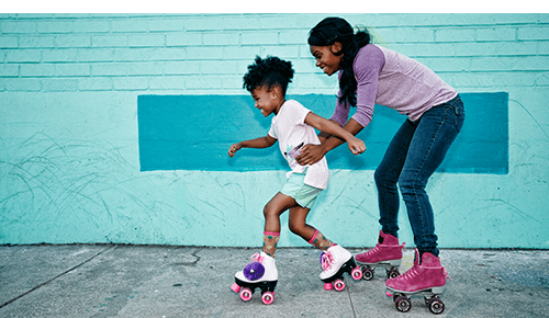 Adult and child roller skating on sidewalk Adult and child roller skating on sidewalk
