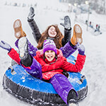 Children laughing while sledding down a hill in a tube