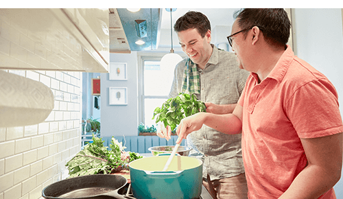 Two smiling people cooking together in kitchen