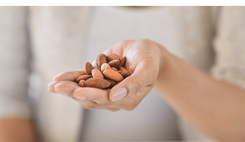 Hand holding raw almonds Hand holding raw almonds