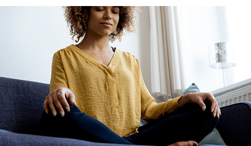 Person meditating with eyes closed on couch