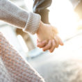Closeup of two people holding hands while walking down the street