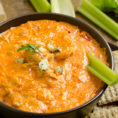 Bowl of buffalo chicken dip with celery sticks and crackers